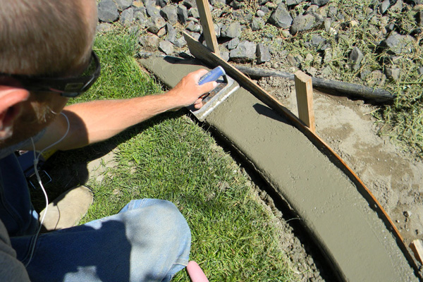 Man smoothing concrete edge in a garden