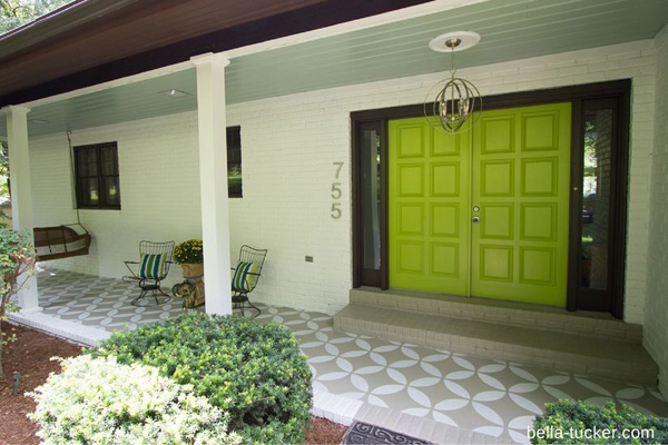 A front porch with a stenciled floor and a bright green door