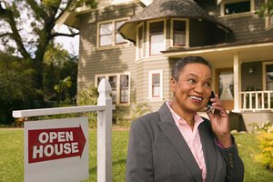 Woman standing next an open house sign in a yard