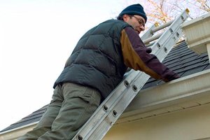 Man cleaning leaves out of gutter