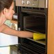 Woman cleaning oven in home kitchen