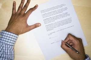 Man's hand signing construction contract