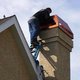 Man replacing chimney cap on house