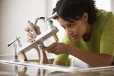 Woman preparing home for sale by fixing faucet