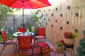 Patio set in back yard of house next to tall privacy fence